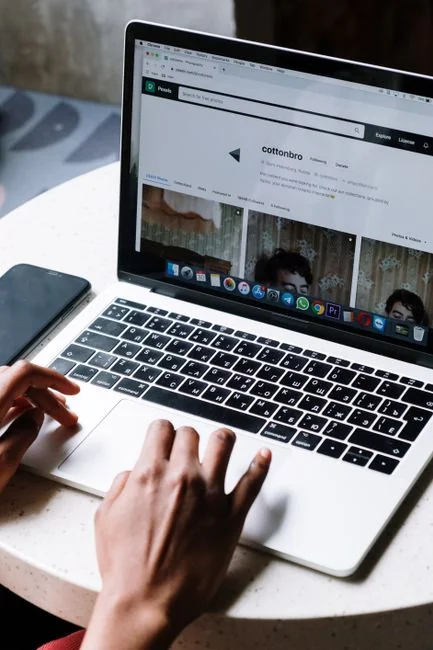 A modern workspace showing hands analyzing marketing data on a laptop and paper documents.